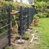 Zwei Männer montieren einen modernen Metallzaun im Garten. Werkzeuge liegen bereit, um den neuen weidezaun garten zu vollenden.