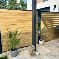 Moderner Sichtschutz aus Holz, ideal zum selber bauen. Ein Grillplatz mit stilvoller Holzwand und Pflanzen.