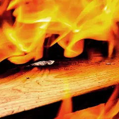 Flammen tanzen über Holz. Lackiertes Holz verbrennen giftig, hinterlässt Asche und Rauch.