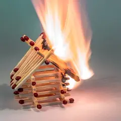 Ein Haus aus Streichhölzern brennt lichterloh. Die Flammen zeigen, ab wann Holz brennt.