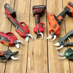 Sechs akku rebschere verschiedener Marken liegen auf Holzbrettern.
