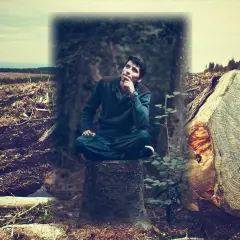 Ein Mann sitzt nachdenklich auf einem Baumstumpf, umgeben von einer Landschaft, in der morsch es Holz brennt.