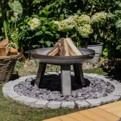 Schöne Feuerstelle im Garten mit Holzkorb und Pflanzen. Tolle Feuerstelle Garten Ideen für gemütliche Abende.