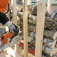 Mann mit Kettensäge bereitet brennholz sägen vor. Holzscheite sind gestapelt und werden für den Winter vorbereitet.