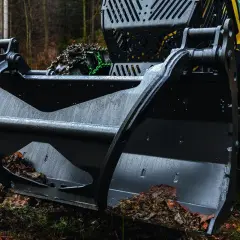 Schwarzer Frontpolterschild mit Erde und Laub gefüllt, bereit für den Einsatz im Wald.