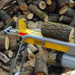 Ein gelber Holzspalter 1m liegt bereit, um den Stapel geschnittener Baumstämme zu bearbeiten.