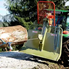 Ein Traktor mit einer **seilwinde** zieht einen Baumstamm aus dem **Wald**.