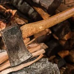Axt liegt auf einem Stapel gespaltenen Holzes. Das Holz ist trocken und bereit, ein gutes Brennholz zu werden.
