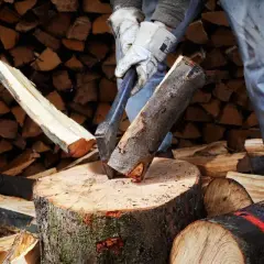 Mann spaltet Holz mit Axt. Mit der richtigen Technik kann man den Holzspalter schneller machen und effizienter arbeiten.