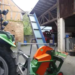 Gebrauchte Kreissäge mit Förderband, bereit für den Holzeinschlag. Ein Traktor steht daneben.