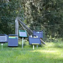 Mehrere solar stromgeräte stehen auf einer sonnigen Wiese, bereit, Tiere sicher einzuzäunen.