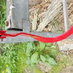 Roter, gebogener Metallarm, Teil eines Baumschiebers, der an einem Metallpfosten befestigt ist.