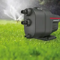 Ein Hauswasserwerk für den Garten, das mit einem Rasensprenger im Hintergrund für eine grüne Oase sorgt.