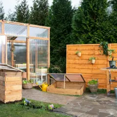 Ein Garten mit einem selbstgebauten Tomatenhaus, Frühbeet und einer Werkbank. Perfekt für alle, die ihr Tomatenhaus selber bauen möchten.