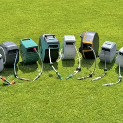 Reihe von schlauchaufroller garten Modellen in verschiedenen Farben und Designs, auf grünem Rasen arrangiert.