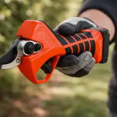 Eine Hand mit Handschuh hält eine leuchtend orangefarbene Rebschere.