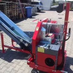 Rote Maschine mit einem langen, schrägen Förderband, bereit für den Einsatz. Diese Kreissäge mit Förderband ist ein robustes Gerät für die Holzverarbeitung.