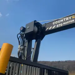 Ein Kranarm mit der Aufschrift "COUNTRY 670 MASTER" und Seilwinden, bereit für den Einsatz. Die robusten Seile erinnern an starke **Chokerketten**.