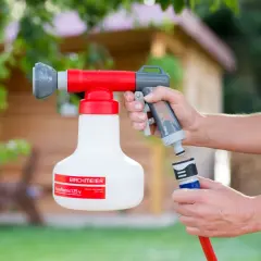 Eine Hand hält ein rot-graues Gerät, das wie ein **Düngermischgerät** aussieht. Ein Schlauch wird angeschlossen.