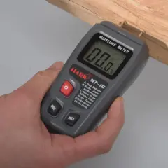 Ein Feuchtigkeitsmesser misst den Wassergehalt in Holz. Hier wird er an einem Holzstück angewendet.
