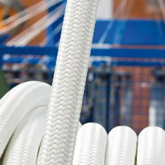 Ein dickes, weißes Seil liegt auf einer Seilwinde. Der Hintergrund zeigt eine Maschine, die bereit ist, das Seil zu wechseln.