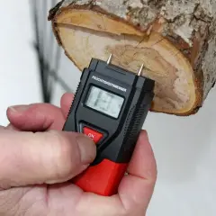 Ein Feuchtigkeitsmesser misst den Feuchtigkeitsgehalt von Brennholz. Die Anzeige zeigt 13%.