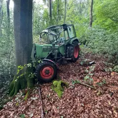 Ein grüner Traktor, der wie eine Bandsäge aussieht, steht im Wald.