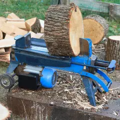 Ein Holzspalter mit einem dicken Holzstamm, bereit, dickes Holz zu spalten. Daneben liegen bereits gespaltene Holzscheite.