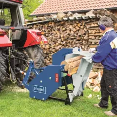 Mann bedient eine gebrauchte Scheppach Rolltischkreissäge mit Zapfwellenantrieb, bereit zum Holzhacken neben einem Traktor.