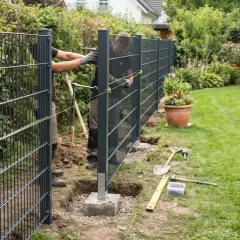 Zwei Männer montieren einen modernen Metallzaun im Garten. Werkzeuge liegen bereit, um den neuen weidezaun garten zu vollenden.
