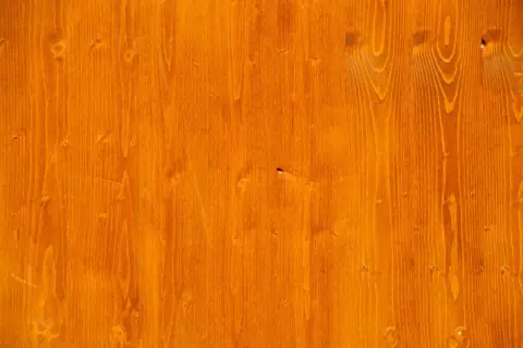 Orange gebeiztes Birken-Weichholz mit sichtbarer Maserung und Astlöchern.