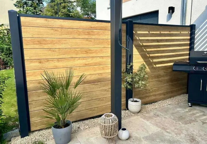Moderner Sichtschutz aus Holz, ideal zum selber bauen. Ein Grillplatz mit stilvoller Holzwand und Pflanzen.