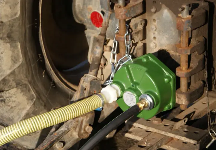 Grüne Zapfwellenpumpe mit Schläuchen an einem Traktor.