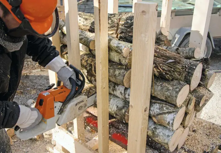 Mann mit Kettensäge bereitet brennholz sägen vor. Holzscheite sind gestapelt und werden für den Winter vorbereitet.