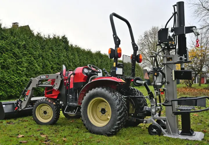 Roter Traktor mit Frontlader und einem liegenden Holzspalter gebraucht 30t im Garten.