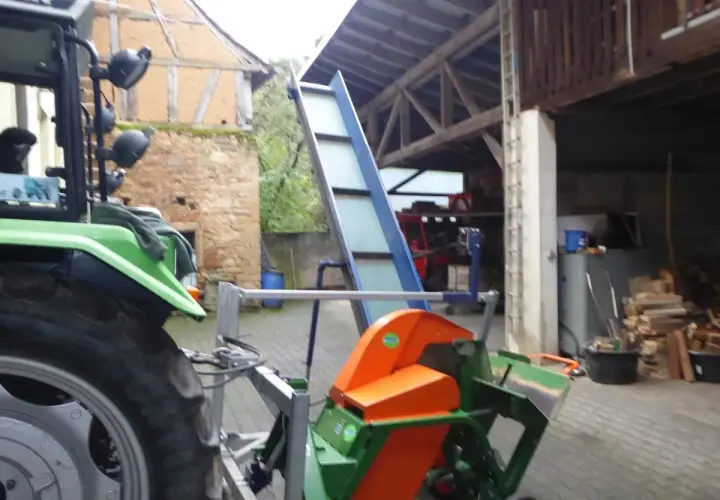 Gebrauchte Kreissäge mit Förderband, bereit für den Holzeinschlag. Ein Traktor steht daneben.