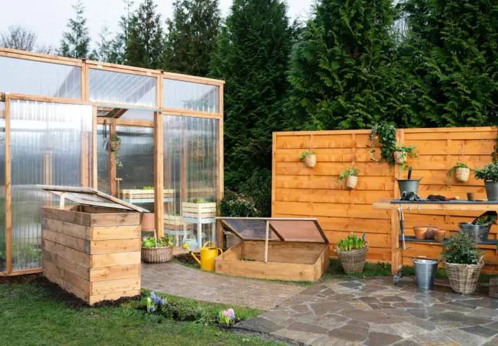 Ein Garten mit einem selbstgebauten Tomatenhaus, Frühbeet und einer Werkbank. Perfekt für alle, die ihr Tomatenhaus selber bauen möchten.