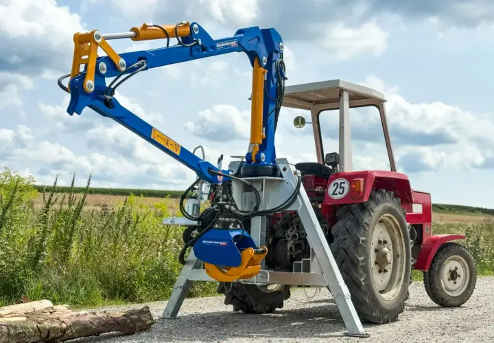 Ein blauer Binderberger 3-Punkt-Kran für Traktoren, gebraucht, mit Greifer, bereit für den Holzeinsatz.