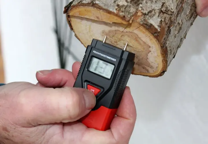 Ein Feuchtigkeitsmesser misst den Feuchtigkeitsgehalt von Brennholz. Die Anzeige zeigt 13%.