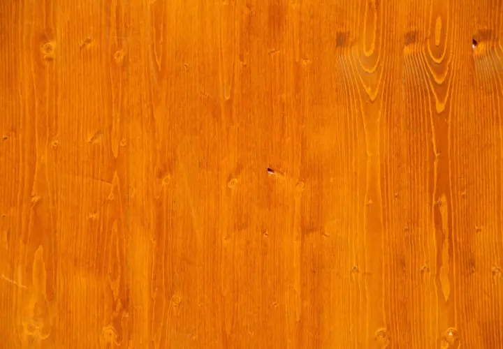 Orange gebeiztes Birken-Weichholz mit sichtbarer Maserung und Astlöchern.