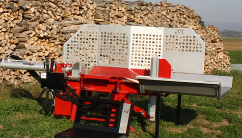 Roter Holzspalter mit 20T-Aufschrift, bereit für das nächste Holzspalter-Angebot. Im Hintergrund ein großer Stapel gespaltenes Holz.