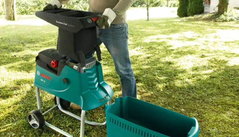 Gartenarbeit leicht gemacht: Ein Mann bedient einen Bosch Häcksler, den meister shredder, im Garten.