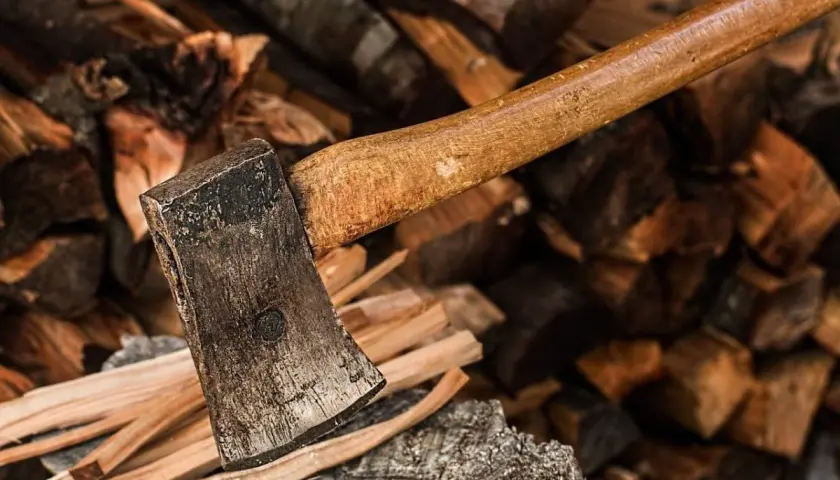 Axt liegt auf einem Stapel gespaltenen Holzes. Das Holz ist trocken und bereit, ein gutes Brennholz zu werden.