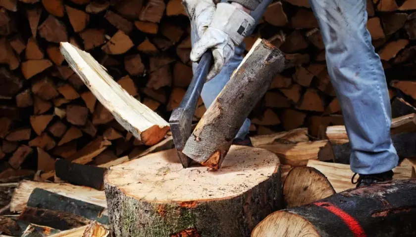 Mann spaltet Holz mit Axt. Mit der richtigen Technik kann man den Holzspalter schneller machen und effizienter arbeiten.