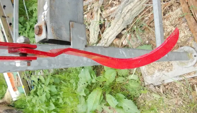 Roter, gebogener Metallarm, Teil eines Baumschiebers, der an einem Metallpfosten befestigt ist.