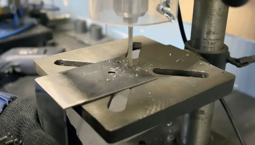 Detailaufnahme des Aufbaus einer Standbohrmaschine, die ein Metallstück bohrt.