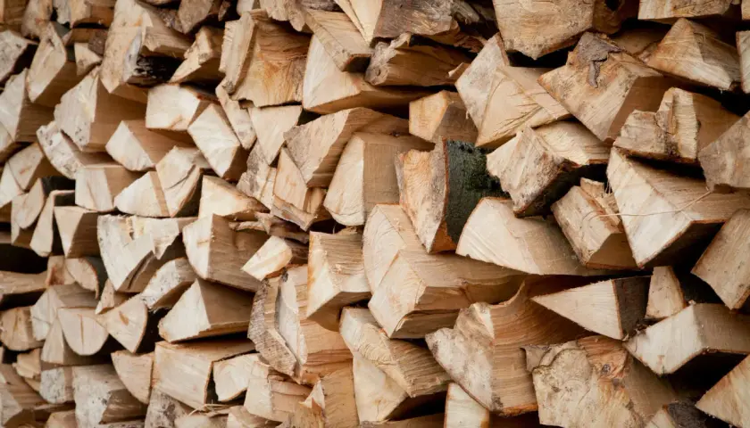 Ein Stapel gespaltenes Holz, bereit zum Bongossi Holz verbrennen. Die Maserung und die Rinde sind gut sichtbar.