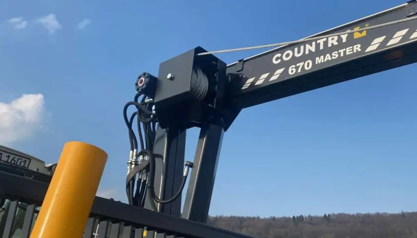 Ein Kranarm mit der Aufschrift "COUNTRY 670 MASTER" und Seilwinden, bereit für den Einsatz. Die robusten Seile erinnern an starke **Chokerketten**.