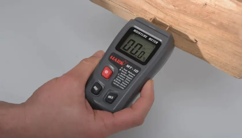 Ein Feuchtigkeitsmesser misst den Wassergehalt in Holz. Hier wird er an einem Holzstück angewendet.