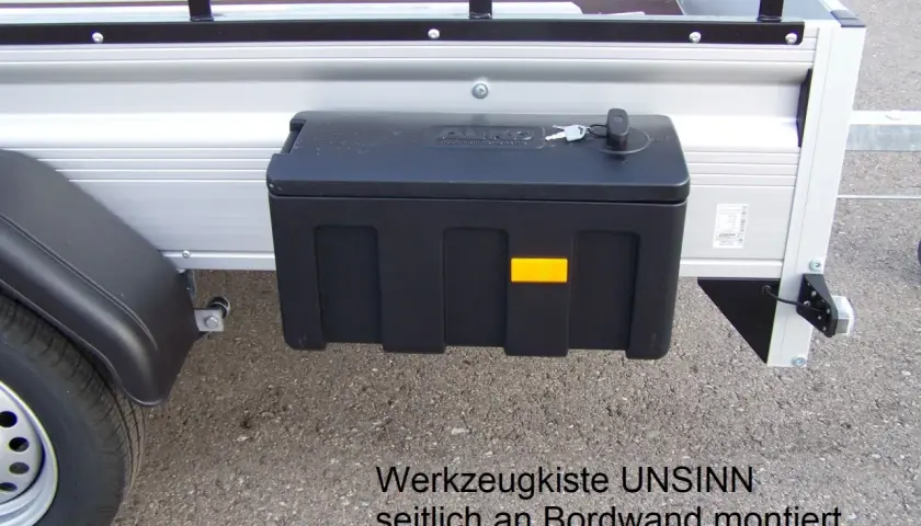 Schwarze Werkzeugbox seitlich am Anhänger montiert, mit Schlüssel.